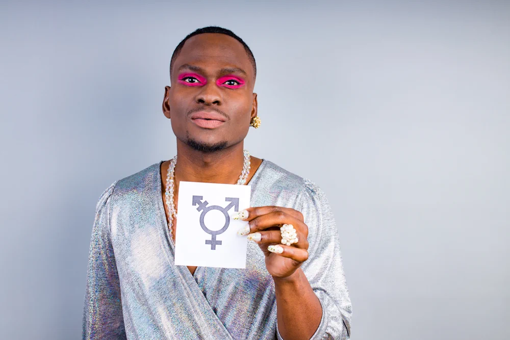 Homem negro segurando um papel com o símbolo trans